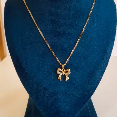 colar com pingente de laço dourado com pedras